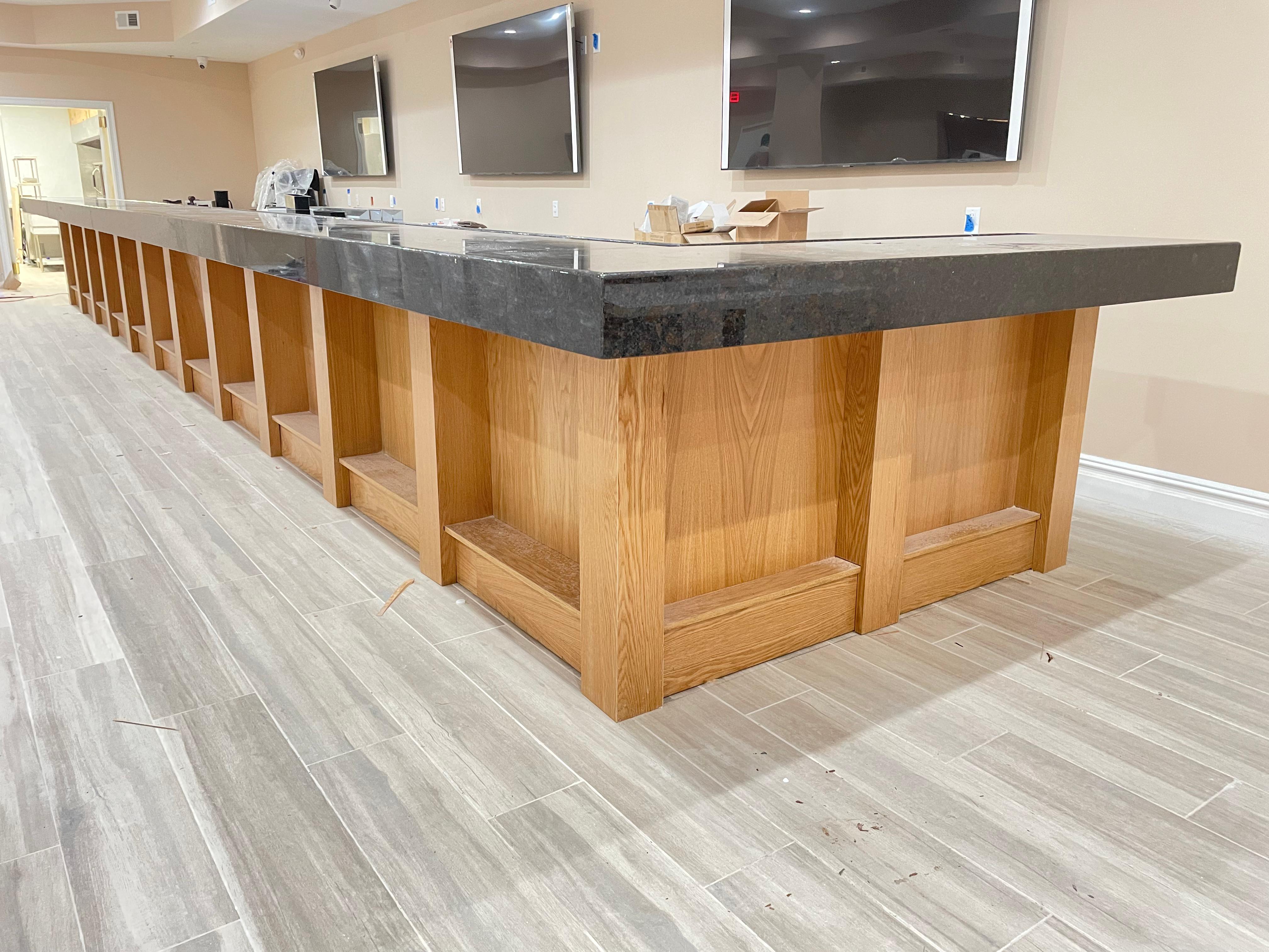 Custom wood and dark granite bar millwork by Mozy Construction
