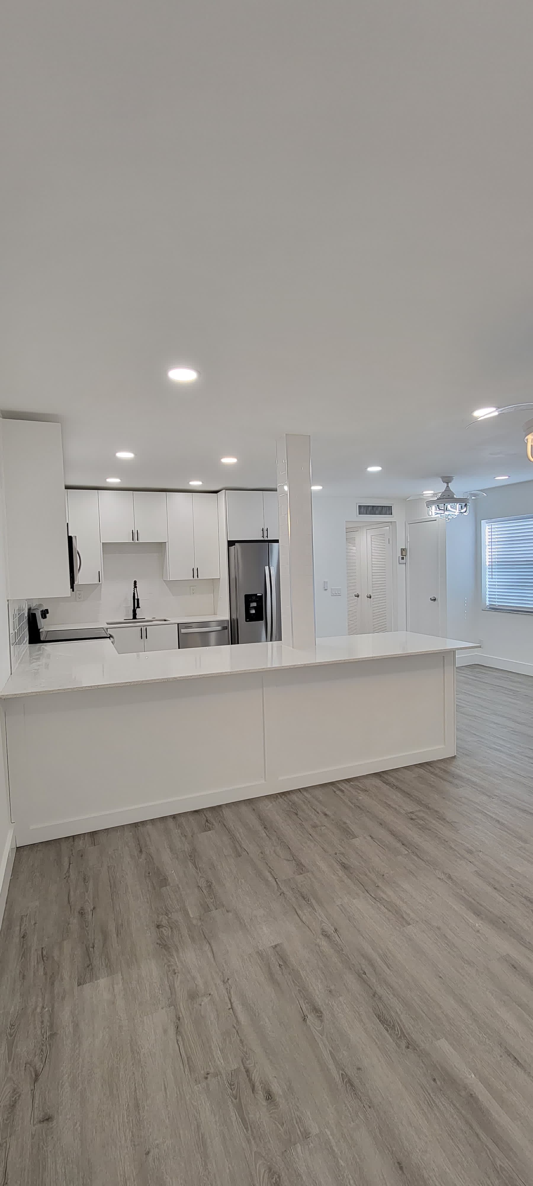 Bright white open-concept kitchen remodel with island and luxury vinyl flooring by Mozy Construction