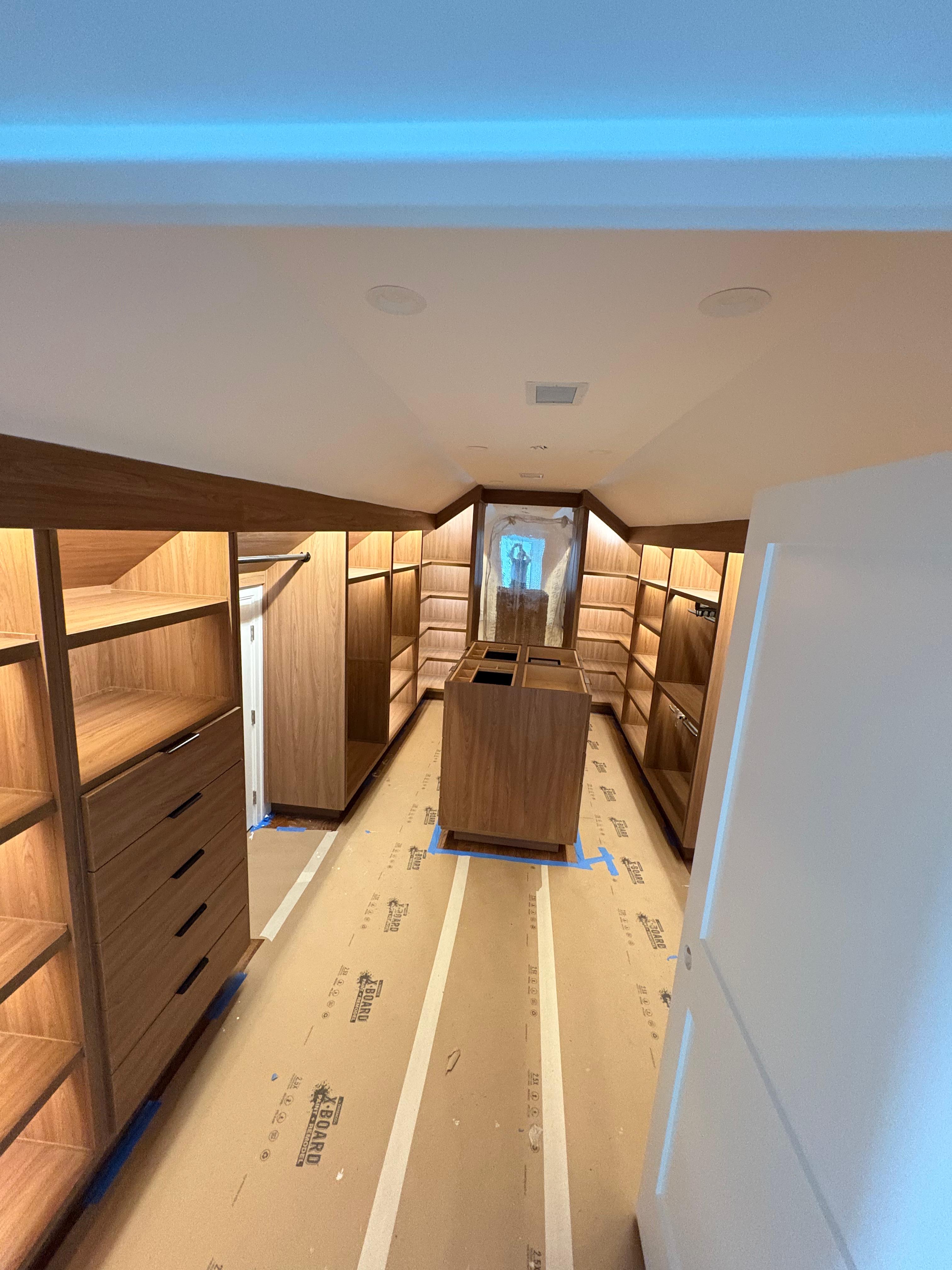 Custom walk-in closet with wood built-ins and LED lighting by Mozy Construction